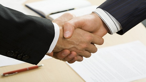 Photo of business handshake over workplace Photo of business handshake over workplace